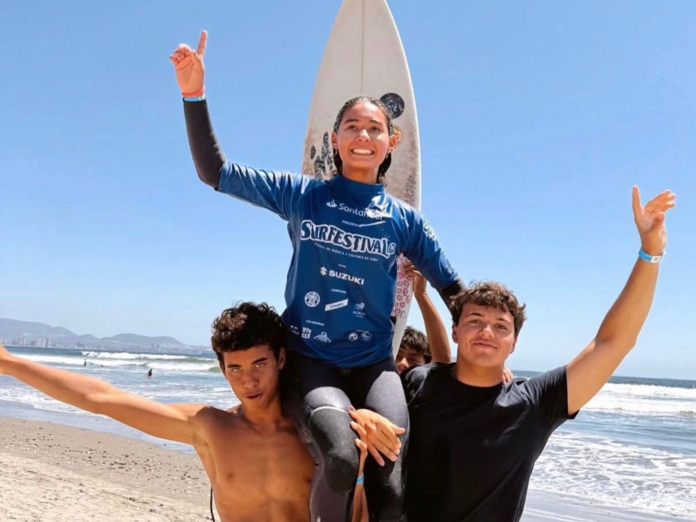 A young surfer carried on friends' shoulders after a win