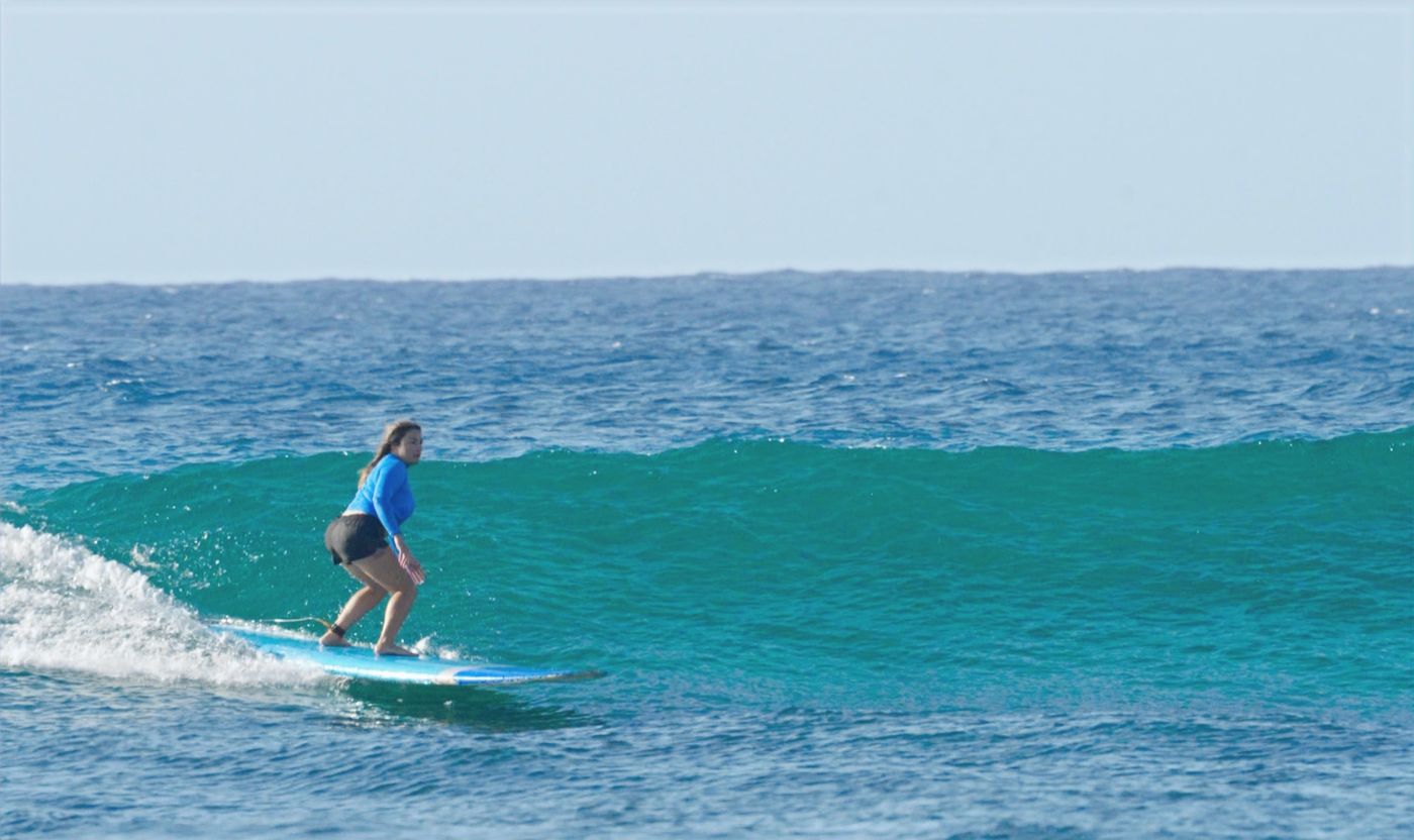 A surfer rides a turquoise wave